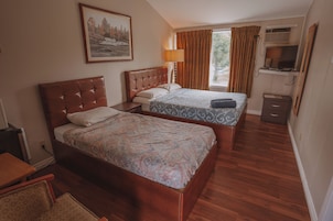 Habitación de hotel con dos camas, televisión, escritorio y ventana con cortinas.