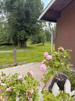 Un jardín con un sendero de grava, una valla de madera y un edificio de ladrillo con techo inclinado.