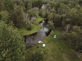 Vista aérea de una propiedad con río, rodeada de bosque denso y una casa al fondo.