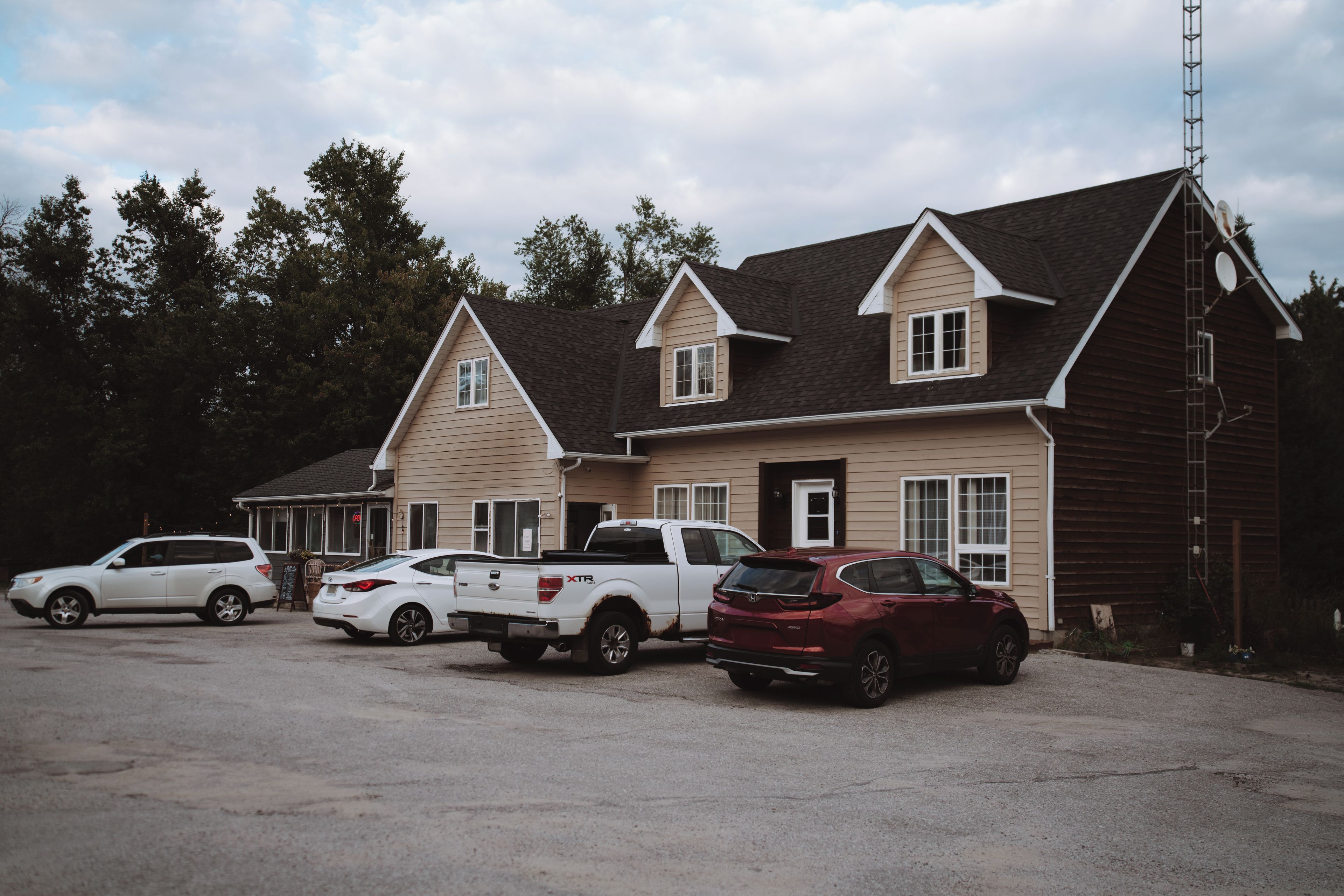 A building with a pitched roof and multiple windows, surrounded by parked cars.