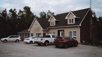 A building with a pitched roof and multiple windows, surrounded by parked cars.
