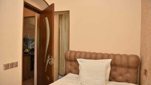 Ein Schlafzimmer mit Bett, einer Tür zum Badezimmer und einer kleinen Küchenzeile.
