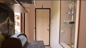 Ein Zimmer mit Holztür, einem kleinen Tisch mit Metallgestell und einer Glasablage mit verschiedenen Gegenständen.