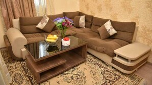 Ein Wohnzimmer mit einem braunen Sofa, einem Glastisch und einem kleinen Beistelltisch.