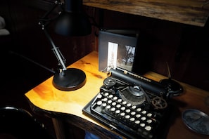 Una máquina de escribir Underwood antigua sobre un escritorio de madera con una lámpara y un letrero de bienvenida.