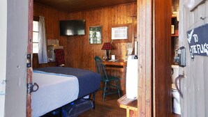 A wooden cabin room with a bed, a desk, a chair, a television, and a sign. - Cabin #9 -" Flag-up " (Cadillac)