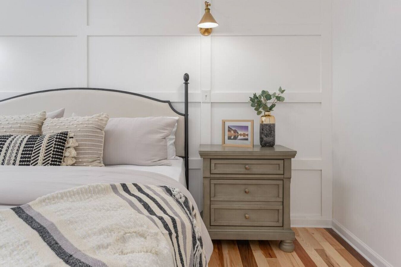 Une chambre à coucher avec un lit, une table de chevet et un luminaire fixé au mur.