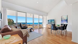 A spacious living room with a large sliding glass door leading to a beach view. - Malua Dream on Kuppa Avenue (MALUA BAY)