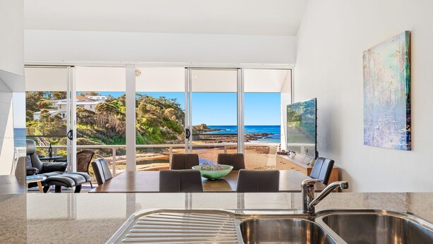 A modern kitchen with a large window overlooking a beach and ocean view. - Malua Dream on Kuppa Avenue (MALUA BAY)