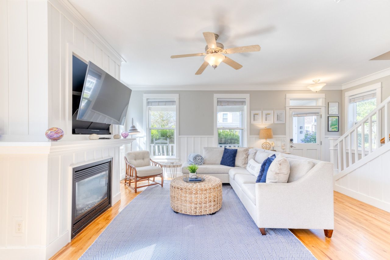 A living room with a fireplace, television, sofa, and a ceiling fan.