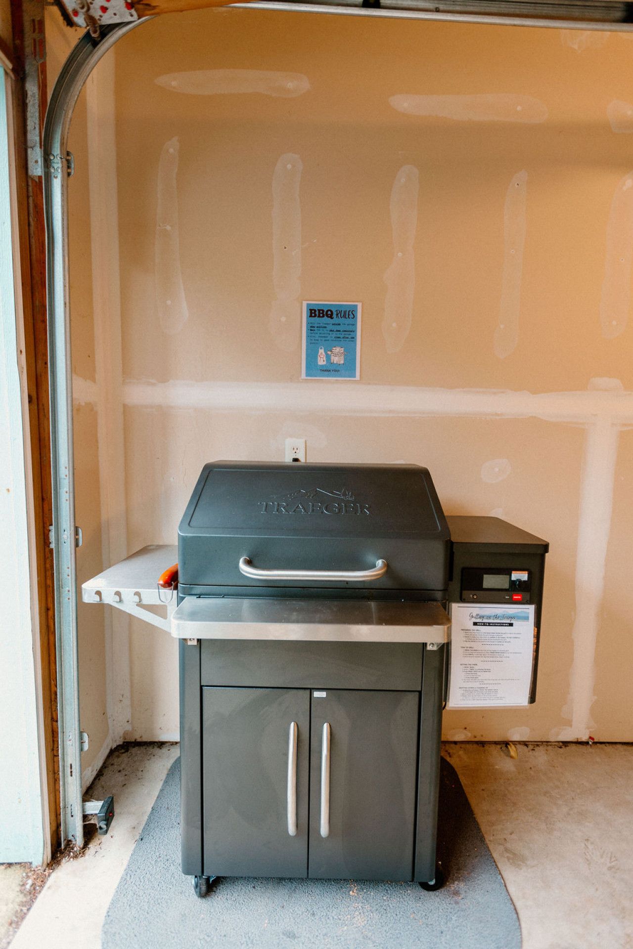 A barbecue grill with a control panel and a sign with BBQ rules.