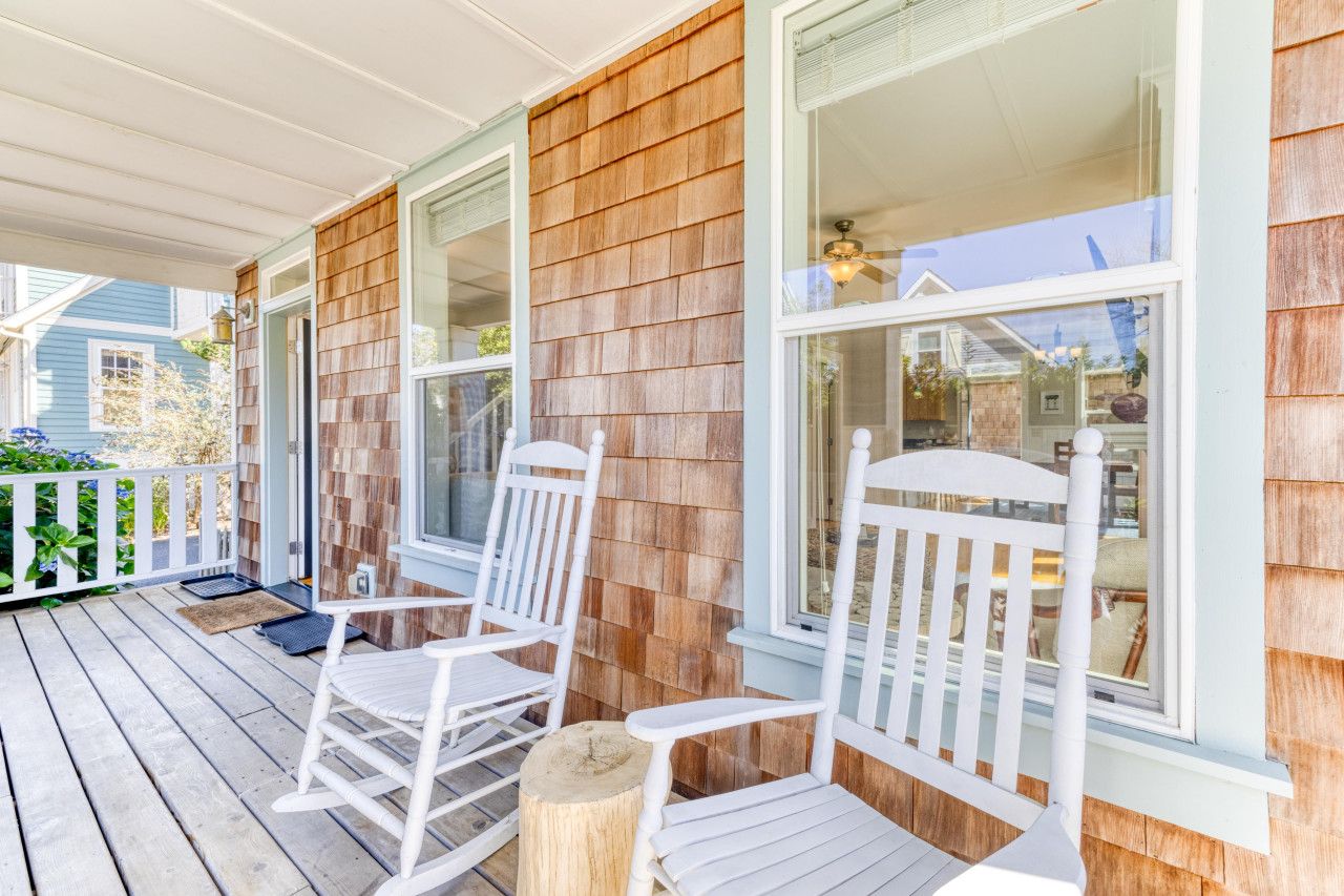 A porch with white rocking chairs and a wooden deck.