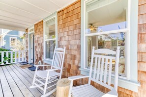 A porch with white rocking chairs and a wooden deck.