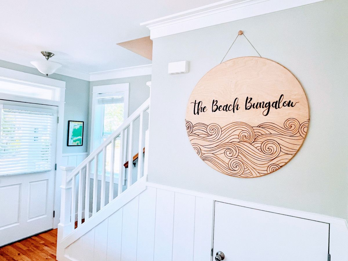 A staircase with a wooden wall hanging that reads 'the Beach Bungalow'.