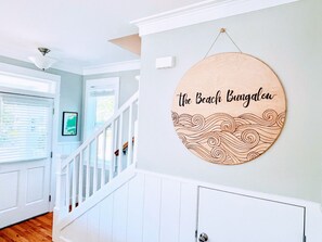 A staircase with a wooden wall hanging that reads 'the Beach Bungalow'.