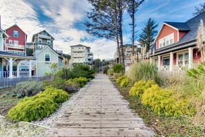 A wooden pathway leading to a row of colorful houses with balconies, surrounded by lush greenery.