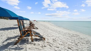 A beach with wooden beach chairs and a blue umbrella. - KonoVilla * Dog Friendly * Best Lagoon Pool in Destin (Destin)