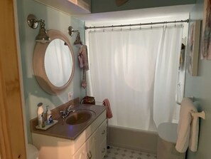 Un baño con lavamanos, espejo e inodoro.