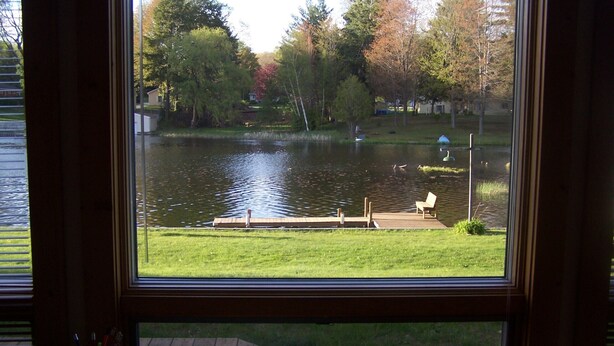 A view of a lake with a dock and a bench, surrounded by trees and a grassy area. - Maggies on the Bayou, close to Hiking, Beaches, Boating, Golf (Ludington)