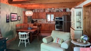 A cozy interior with a dining area, a sofa, and a kitchen with wooden cabinets and appliances. - Maggies on the Bayou, close to Hiking, Beaches, Boating, Golf (Ludington)