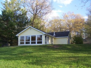 A single-story house with a gabled roof and large windows on the front.