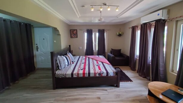 A bedroom with a bed, a sofa, a desk, and a ceiling fan.