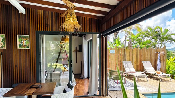 Una terraza de madera con piscina, sillas de descanso y una lámpara colgante.