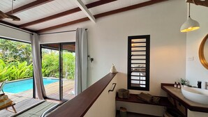 Un baño con un banco de madera, un lavamanos y una ventana con persianas.