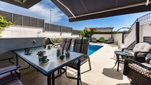 Eine Terrasse im Freien mit Pool, Sitzgelegenheiten und einem überdachten Bereich.