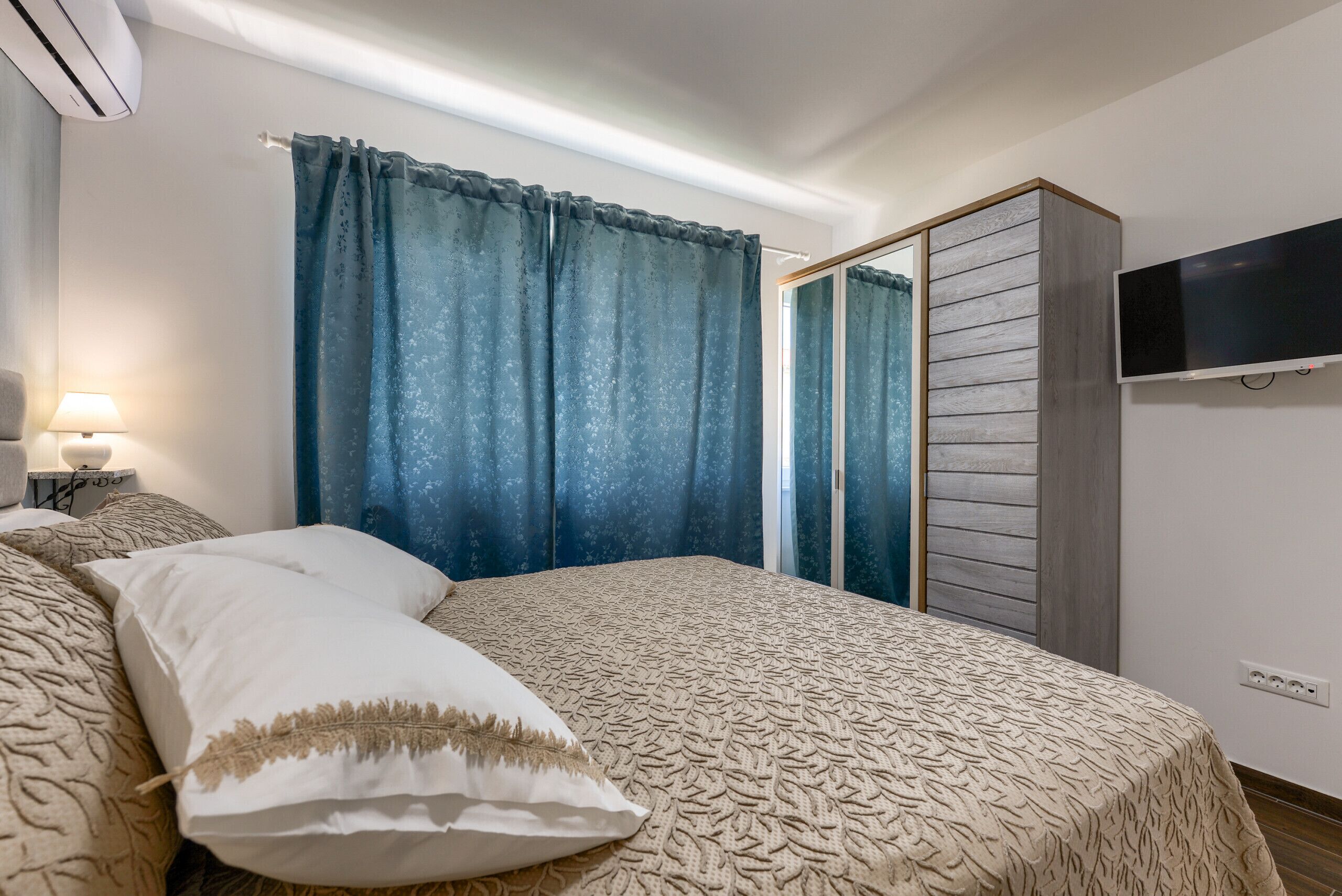 A bedroom with a bed, a nightstand, a TV, and a wardrobe.