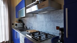 Une cuisine moderne avec des meubles bleus, une cuisinière à gaz, un four à micro-ondes et une machine à café.