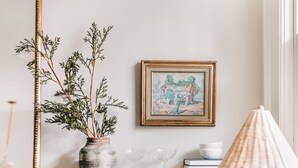 A kitchen with a marble countertop, a white pitcher, a glass jar, a wooden tray with baked goods, and a vase with branches. - Designer Retreat in Quaint Historic District w Front Porch Dining under the oaks (Greenville)