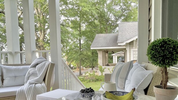 A covered outdoor seating area with a table, chairs, and a potted plant. - Designer Retreat in Quaint Historic District w Front Porch Dining under the oaks (Greenville)