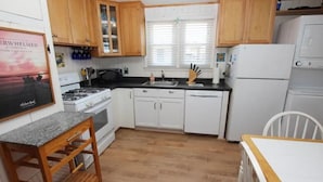 A compact kitchen with wooden cabinets, a gas stove, a sink, and a refrigerator. - "The Hammock Cottage" (Kill Devil Hills)