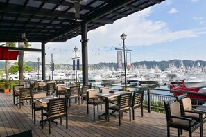 Guests can enjoy waterfront dining and relaxation on the deck, overlooking the marina with docked boats.
