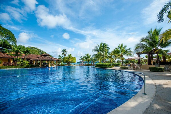 Relax by the pool surrounded by lush gardens and palm trees.