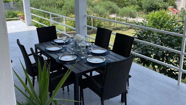 A covered outdoor dining area with a table set for six, surrounded by chairs, and overlooking a scenic landscape. - Click Here - Get Promo Price By Inquiry - Apartments Nenna With 3 Bedrooms (Mravince)