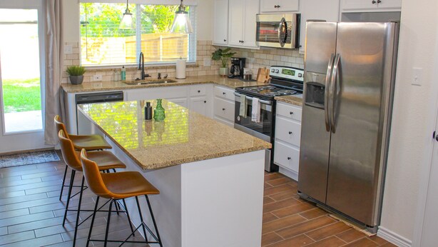 A modern kitchen with a central island, stainless steel appliances, and a view to the outdoors.