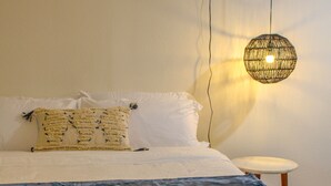 A bed with a white and blue blanket, a white pillow, and a decorative hanging light fixture.
