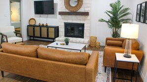A living room with a fireplace, sofa, coffee table, and a television mounted on the wall.