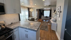 A modern kitchen with white cabinets, a marble countertop, and a built-in stove. - Downtown Darling & Convention Center Home (Salt Lake City)