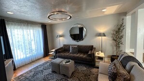 A modern living room with a sofa, ottoman, and a large mirror. - Downtown Darling & Convention Center Home (Salt Lake City)