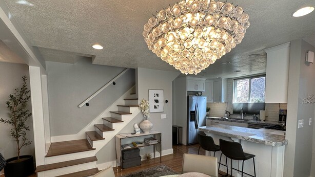 A modern kitchen with a stainless steel refrigerator, a marble countertop, and a chandelier. - Downtown Darling & Convention Center Home (Salt Lake City)
