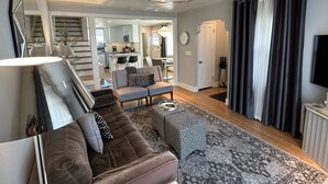 A modern living room with a sofa, ottoman, and a chandelier. There is a staircase leading to a kitchen and dining area. - Downtown Darling & Convention Center Home (Salt Lake City)