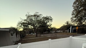 A white wooden fence in a residential area with houses and trees in the background.