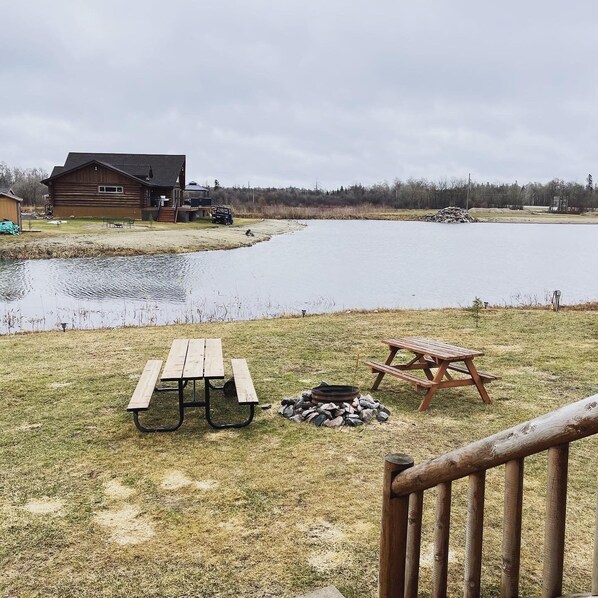 A lakeside cabin with picnic tables and a fire pit.