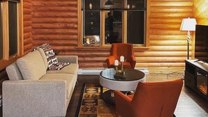 A cozy log cabin interior with a sofa, armchair, and round coffee table.