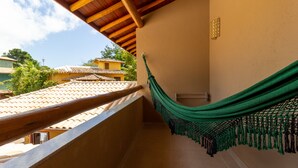 Ein Balkon mit einer grünen Hängematte, gefliestem Boden und Blick auf benachbarte Gebäude.