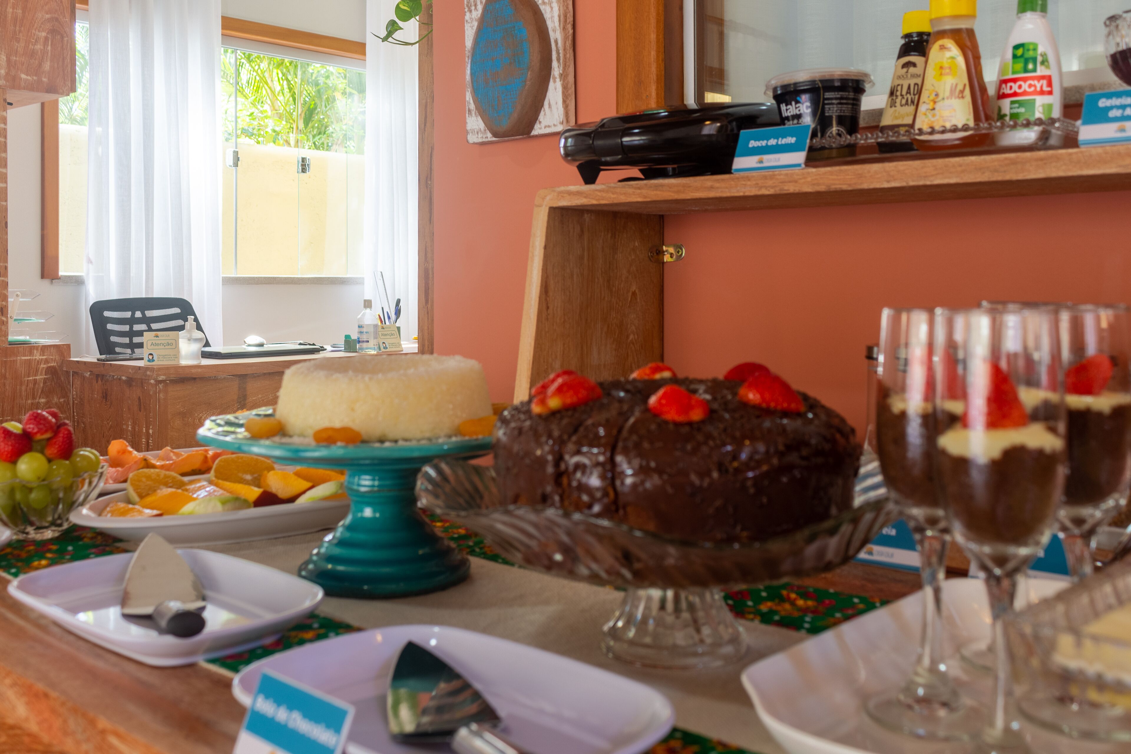 A buffet table with various desserts, including a chocolate cake and fruit platters.