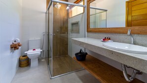 Ein modernes Badezimmer mit einer Duschkabine, einem weißen Waschbecken und einem Holzlagerflächenschrank.